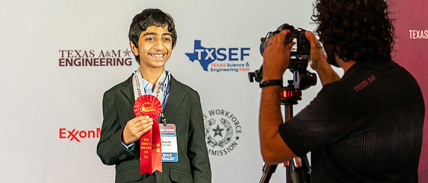 contest participant holding up red award ribbon and smiling at the camera